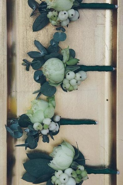 Green and white groom's and groomsmen's flower boutonniere with rose and hypericum berries.
