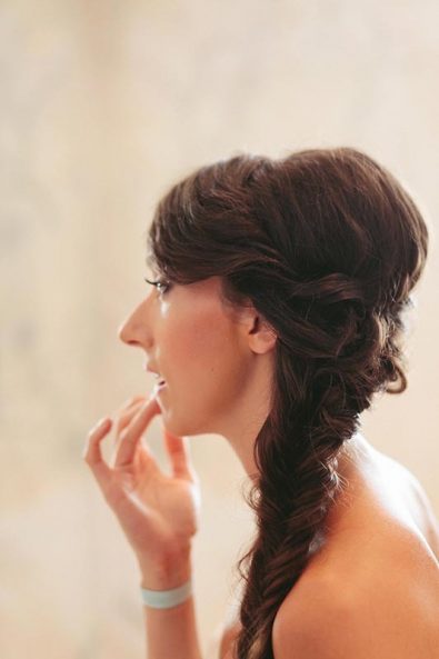 Bride with fishtail bone braid wedding hairstyle getting ready in front of the mirror before her jewish wedding in Athens.