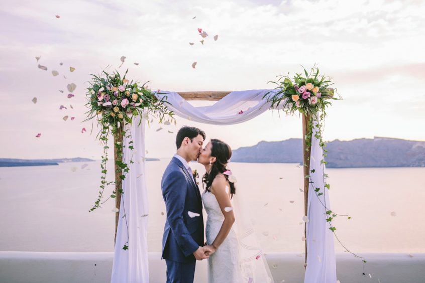 Couple kissing at the wedding aisle at their wedding in Greece, Santorini