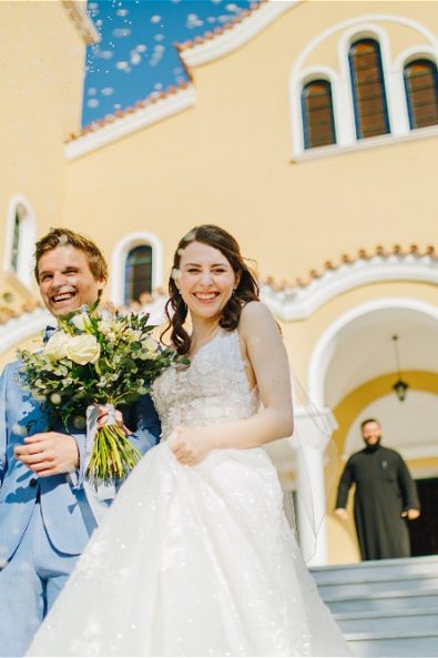Bride and groom walking down church stairs at their destination wedding in Athens Riviera