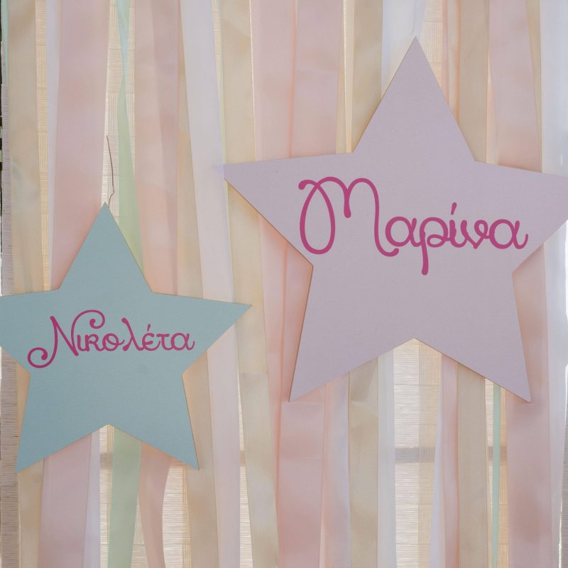 Marina & Nikoleta's baptism details:Paper star decorations on a backdrop with ribbons.