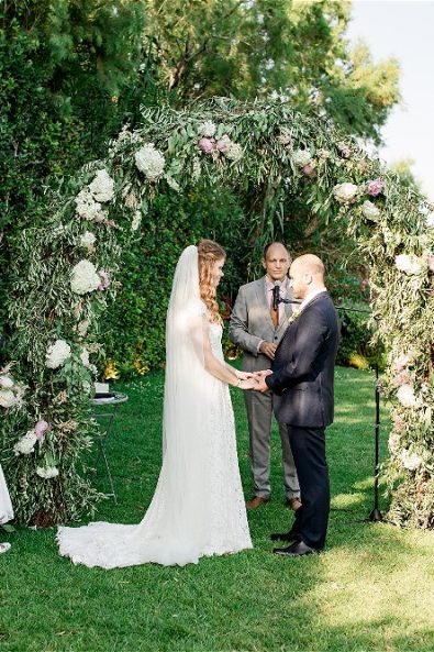 Bride and groom getting married under wedding arch