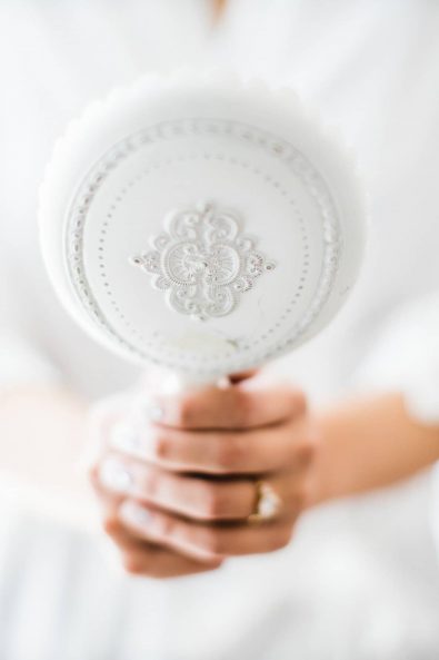 Close up shot of bride holding a vintage white mirror before her destination wedding in Greece.