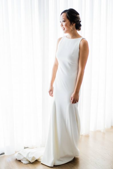 Elegant Korean bride wearing a minimal bridal dress in front of a big window.