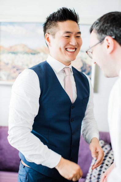 Portrait of the groom getting ready and laughing with his friend before his wedding.