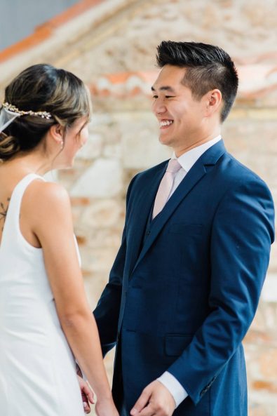 The first look shot of a bride in a minimal wedding dress and groom in a dark blue suit.