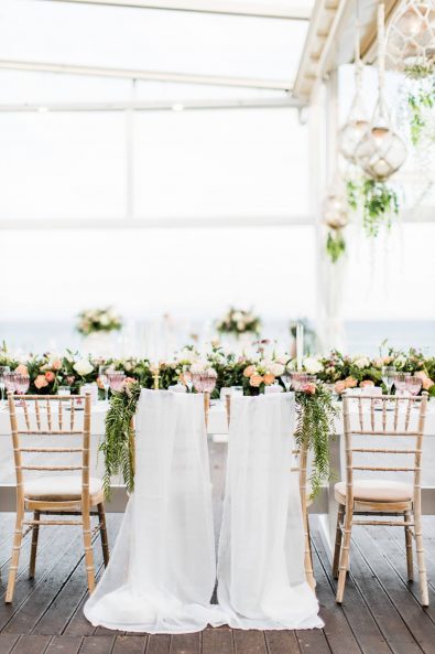 Destination wedding in Greece - White silk and flower design concept for the Bride and Groom's reception chairs for a fine art wedding in Greece.
