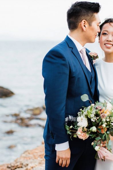 Portrait of bride and groom at the beach looking at each other for and intimate late autumn destination Korean wedding in Greece.