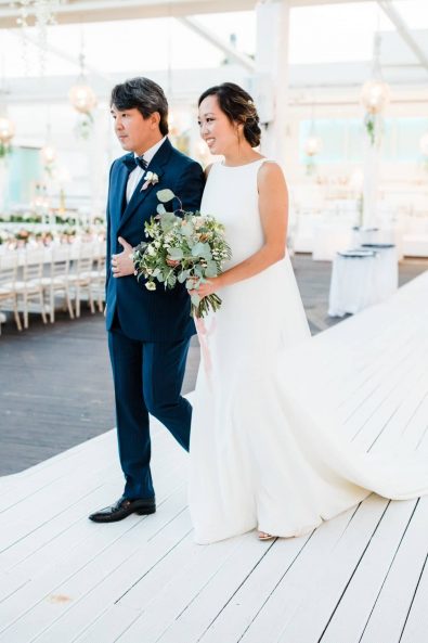 The father of the bride and the bride walking down the aisle.