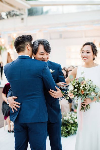 The father of the bride hugging his son in law at the wedding ceremony.