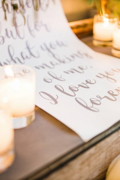 Close up shot of custom made wedding poem printed in grey calligraphy and warm candles.