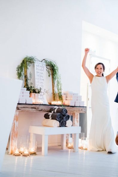 Bride and groom cheering with their hands in the air as they enter their wedding party.