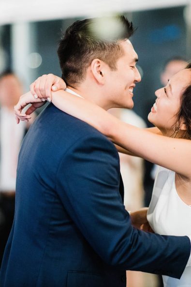 The Korean groom and bride slow dancing at their wedding reception looking lovingly at each other.