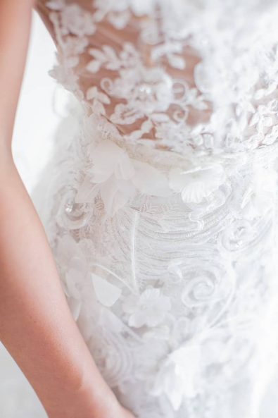 Close up shot of bride's waist wearing her feathers and applique lace wedding dress.