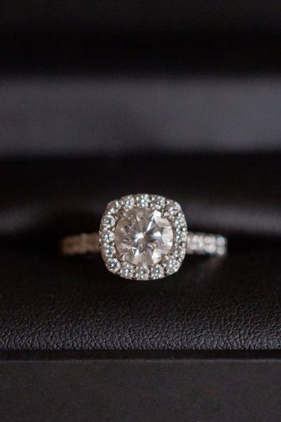 White gold halo diamond engagement ring with two-carat diamond stone and french pave band, in a black leather box.