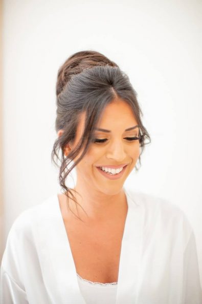 Bridal portrait with a brunette bride with glamorous makeup, bun updo, and white lingerie.
