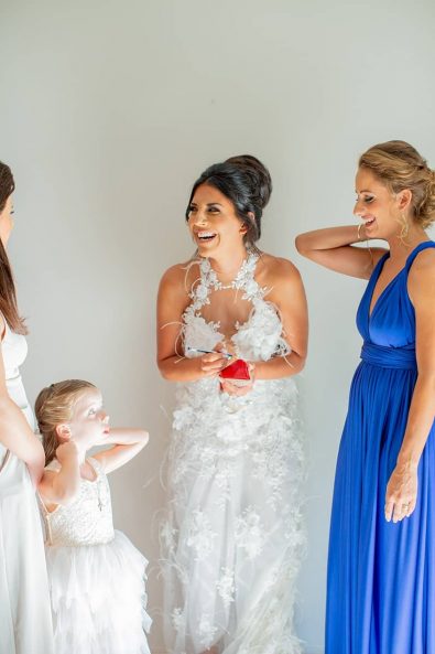 The bride with her friends while she writes names under her Louboutin shoe, a Greek wedding custom.