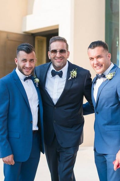 The groom with his two best men posing for a photograph in front of Faneromeni Church in Vouliagmeni Athens for a destination wedding in athenian riviera.