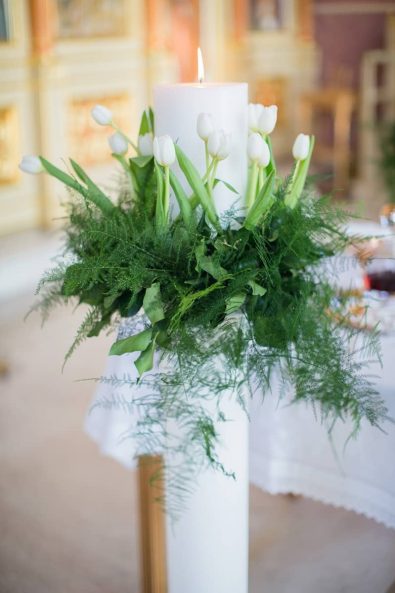 Wedding candle flower decoration with tulips and greenery for a Greek Orthodox wedding.