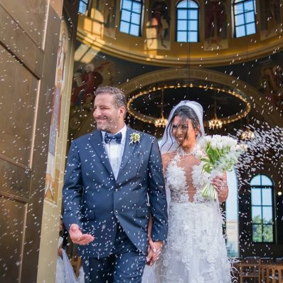 Bride and groom leaving from the church while guests are tossing rice.