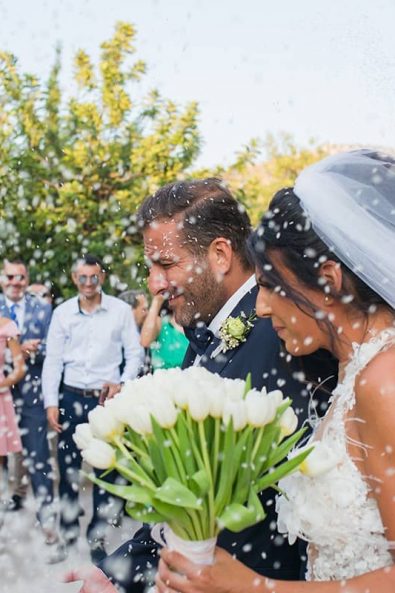 Bride and groom exiting the church after their wedding while the guests are tossing rice to them.