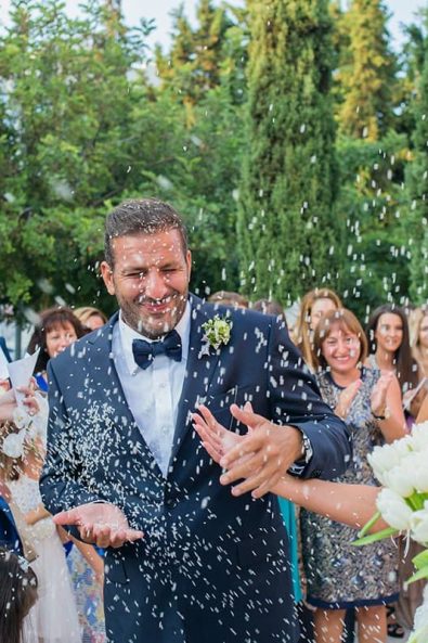 The guests of the wedding throw rice at the newlyweds for good fortune and fertility after their destination wedding in athenian riviera.
