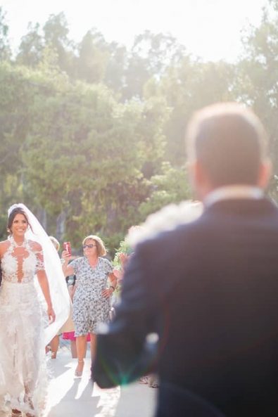 The bride walking toward the groom hand in hand with her father.