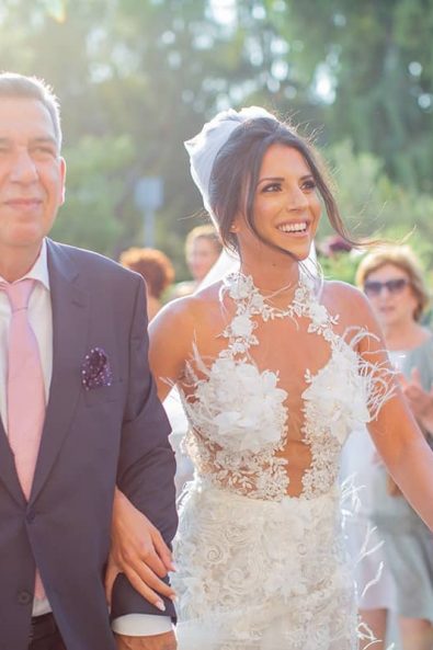 Bride walking hand in hand with her father before he gives her away to the groom at a destination wedding in athenian riviera.