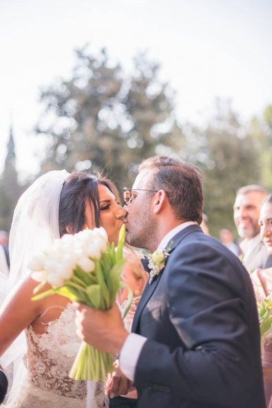 Bride and groom kissing before they get inside the church for their wedding ceremony at a destination wedding in athenian riviera.