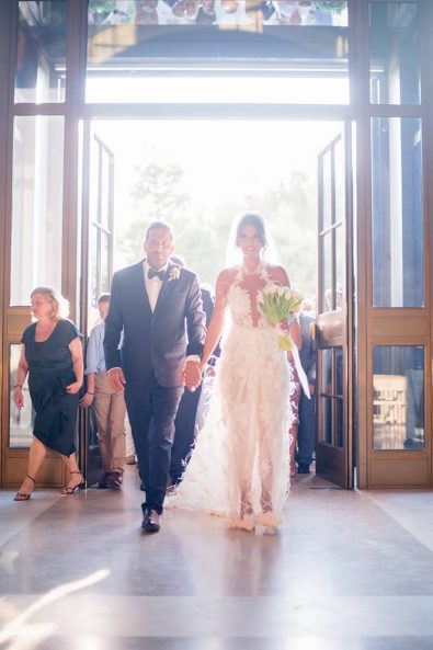 Bride and groom walking hand in hand in the church to get married with a greek orthodox ceremony in Faneromeni in Vouliagmeni, Athens at a destination wedding in athenian riviera.