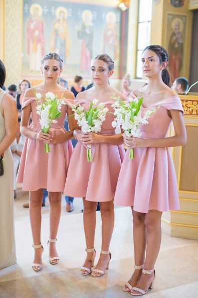 Bridesmaids with romantic blush dresses, tulip and lilies floral bouquets, and nude heels standing next to the bride in the church.