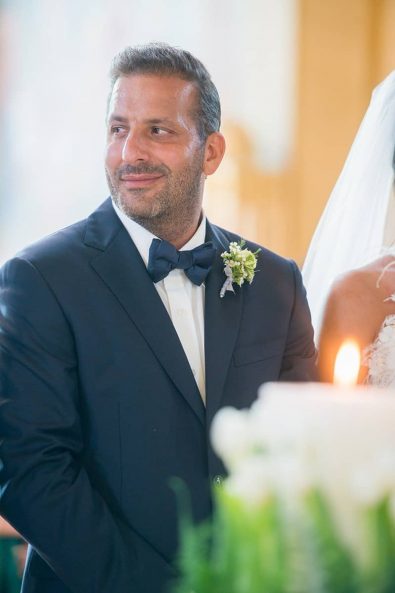 The groom smiling at his wedding ceremony next to his beautiful bride.