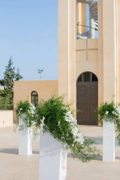 Church flower decoration ideas with white orchids and greenery on a flower stand in Panagia Faneromeni church in Vouliagmeni Athens.