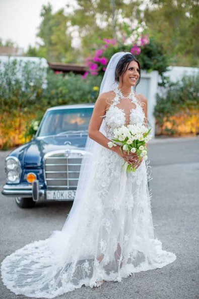 A bride wearing a luxurious sexy a line wedding dress with Louboutin shoes, tulle veil and a white tulip bridal bouquet for a destination wedding in athenian riviera.