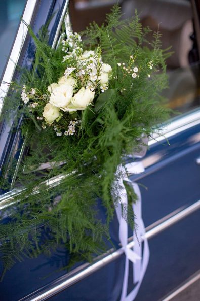 Close up shot of wedding car flower decoration with white roses and greenery.