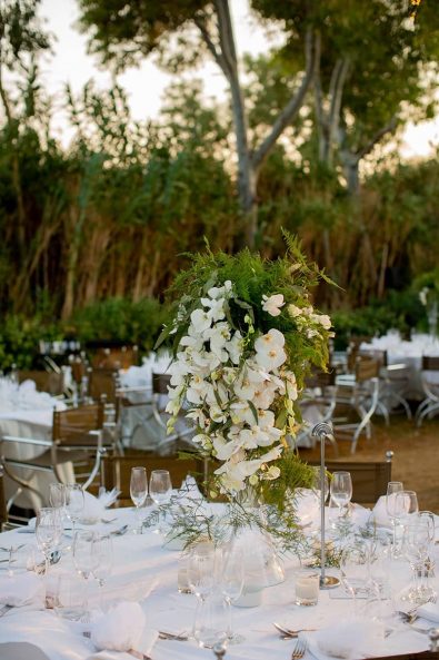Luxurious table centerpiece with white orchids and greenery.