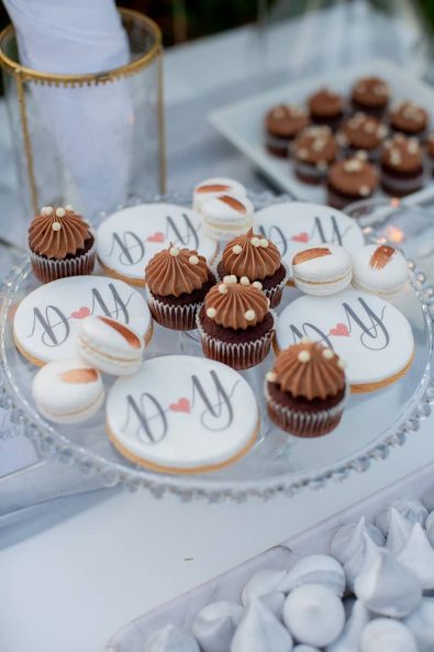 Close up shot of candy bar sweets, chocolate cupcakes, custom made sugar cookies, rosegold decorated macarons and marbled meringues for a destination wedding in athenian riviera.