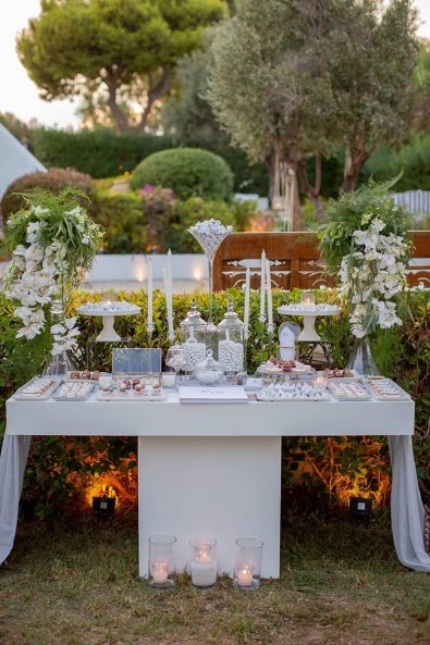 Luxurious and elegant dessert stand candy bar for wedding guests in white and grey shades, with cookies, macarons, custom made wedding dessert and sugar-coated almond koufeta.