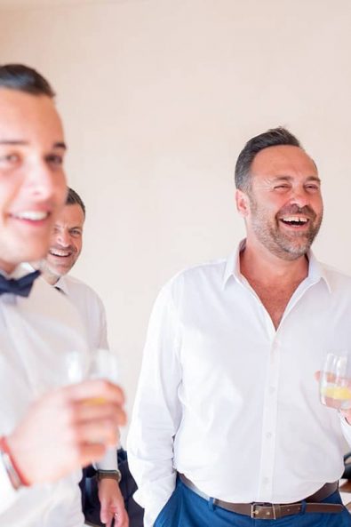 Groomsquad laughing and drinking while the groom is getting ready.