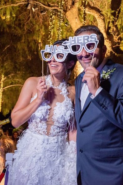 Bride and groom with glasses props at their wedding party photobooth mirror.