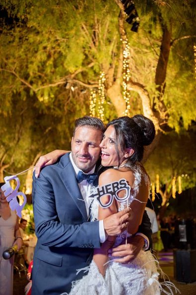 Bride and groom with props taking shots in the photobooth after their destination wedding in athenian riviera.
