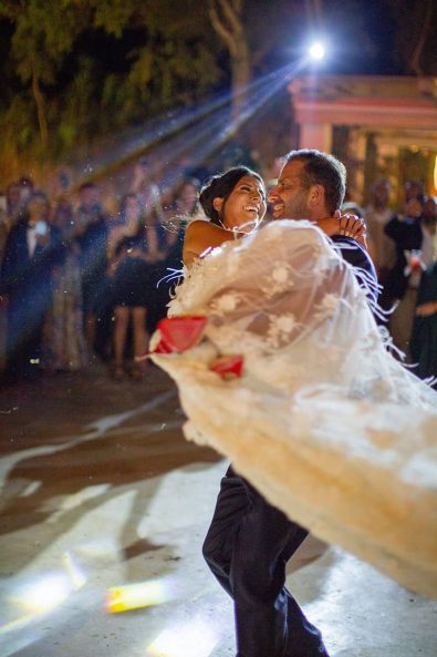 The groom with the bride in his arms dancing in front of the guests.