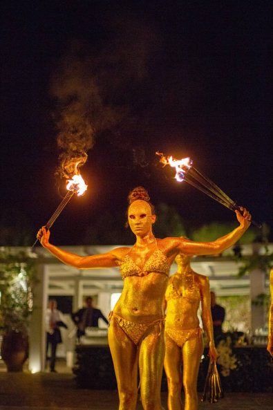 Fire dancing show with dancers wearing gold masks and gold body painting.