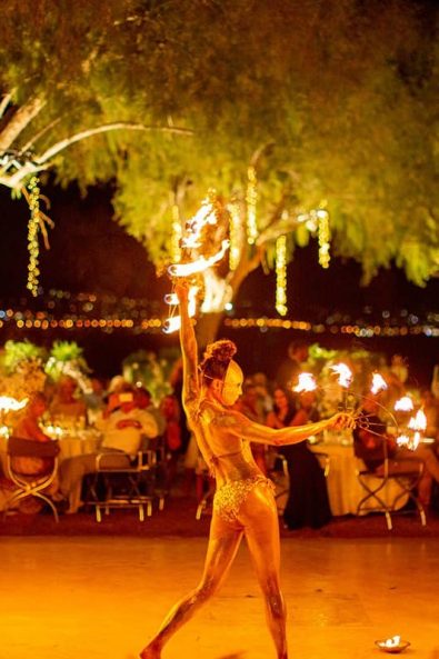 Fire dancers with gold body paint and masks giving a fire dance performance.
