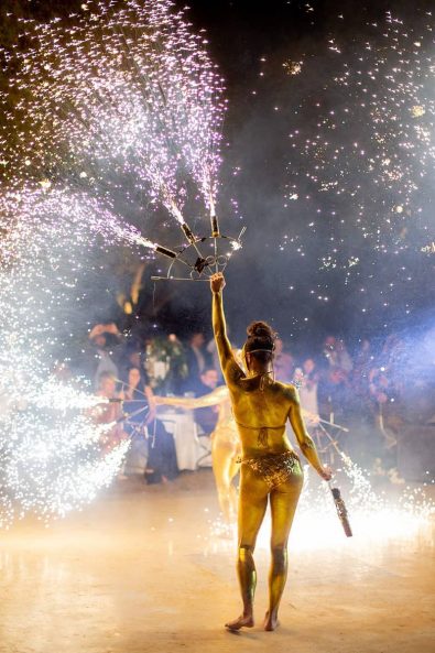 Live Fire dancing show with fireworks and dancers wearing gold bikinis, and gold masks.