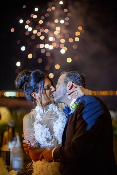 Bride and groom kissing under the firework sky at a destination wedding in athenian riviera.