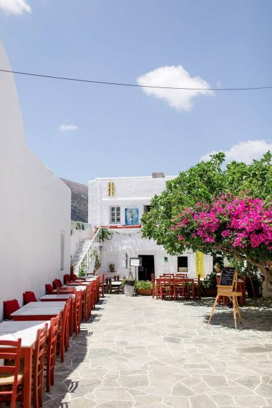 Picturesque greek island square with stone streets, white buildings, and bougainvilia flowers.