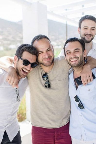 Group shot of groom and his groomsmen drinking champagne laughing.