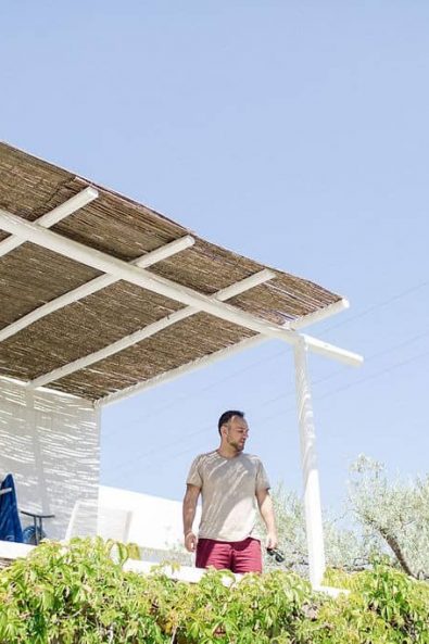 Photo of the groom in a white island house yard with straw sun blinds