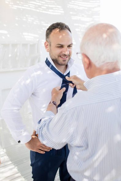 The father of the groom tying his son's necktie before his wedding.